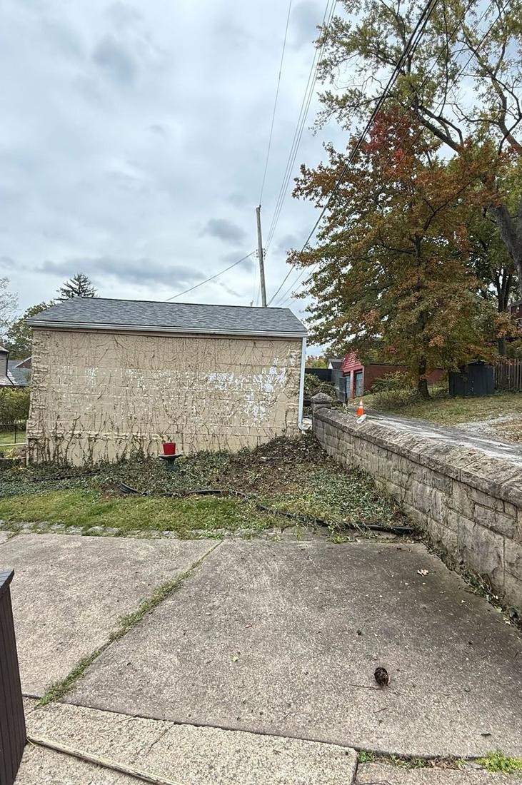 Bare garage wall and cleared stone retaining wall after ivy removal
