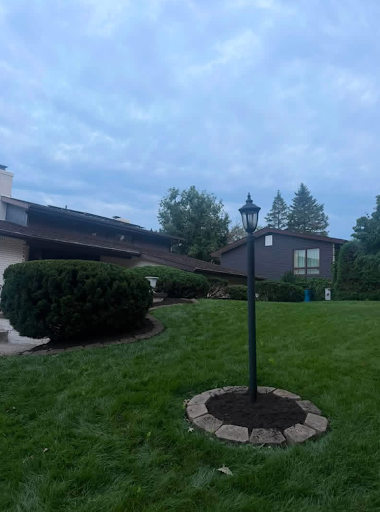 Clean mulch bed around a lamp post with trimmed shrubs and a cut-in bed line