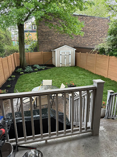 New tan privacy fence and fresh sod lawn around a backyard shed and patio
